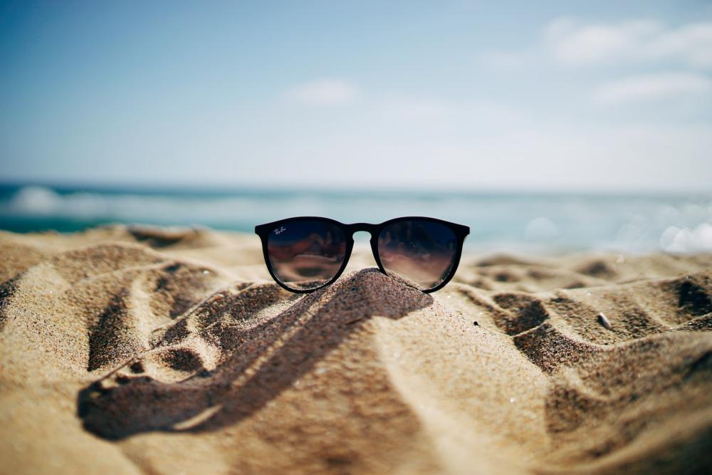 Photo lunettes de soleil posée sur le sable d'une plage